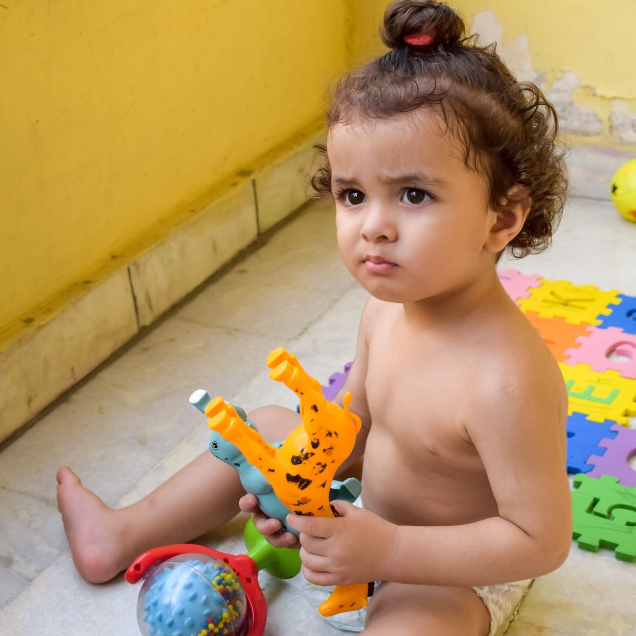 Cute toddler focused on playing with colorful toys indoors on a sunny day